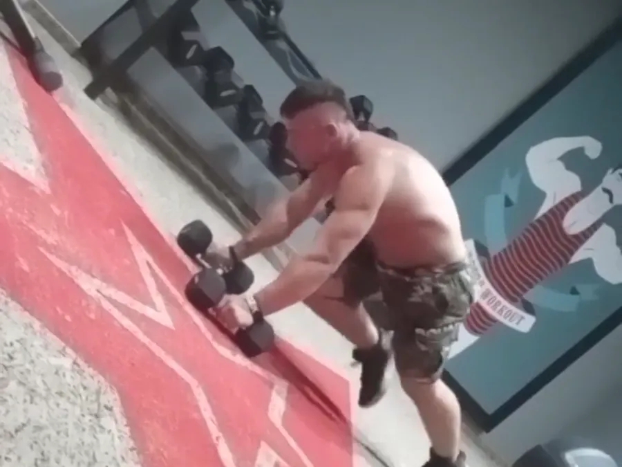 Damian trenuje z hantlami na hotelowej sali w nocy